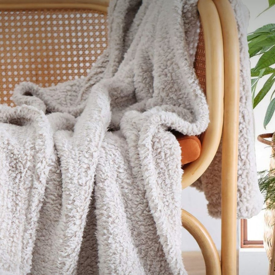 An ultra soft sherpa throw draped over a rattan chair